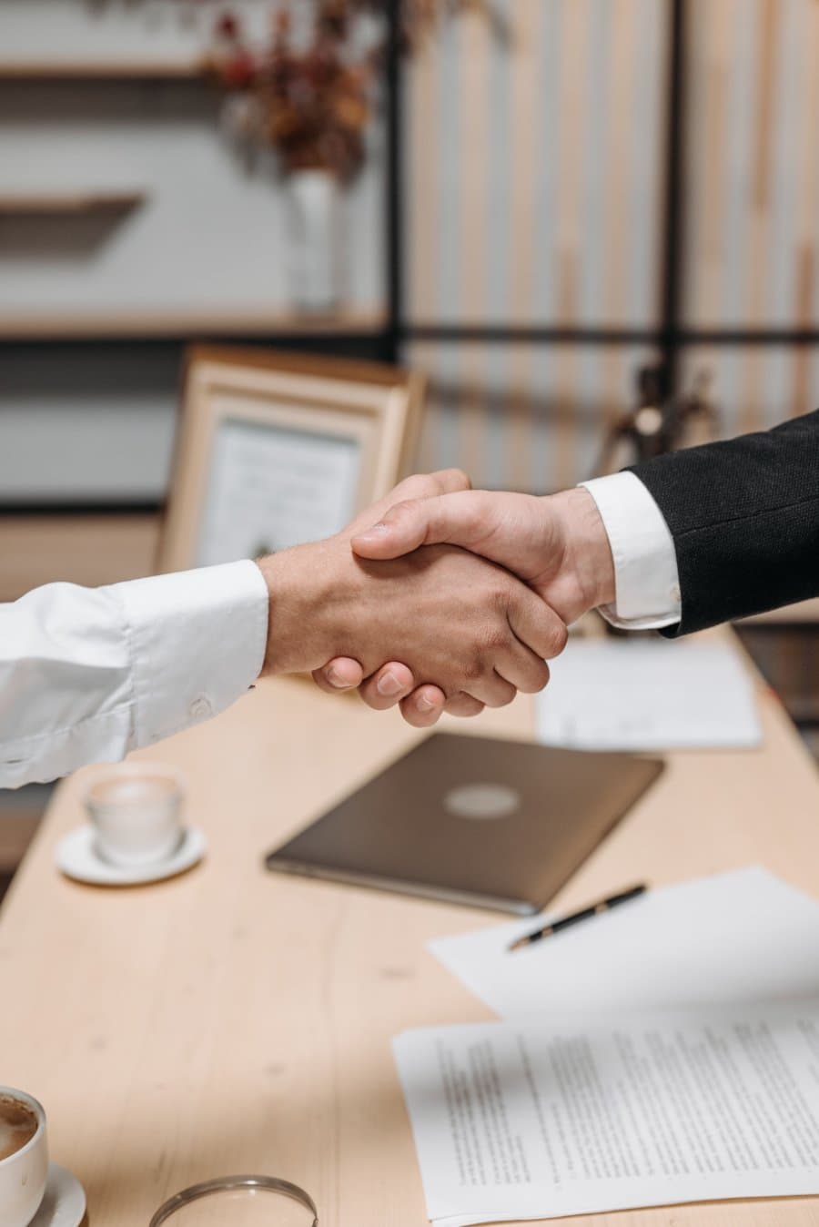 Two people shaking hands across a desk